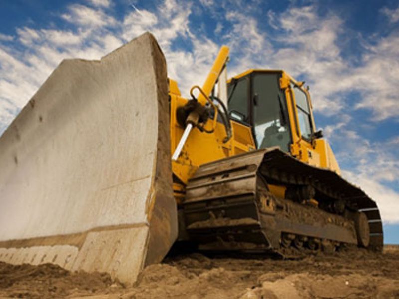 Large bulldozer with a broad scoop preparing a roadway.