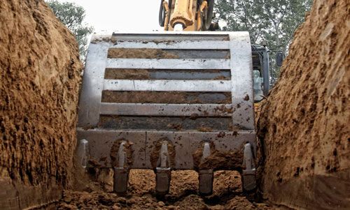 Excavator os scooping a tench for city sewer services.