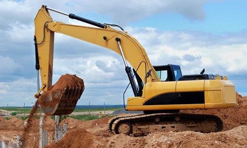 Excavator removing dirt from trench.